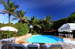 a swimming pool with white chairs and umbrellas at Canto d Alvorada Hotel Pousada in Arraial d'Ajuda