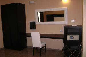 a room with a white chair and a mirror at EH Suites Rome Airport Euro House Hotels in Fiumicino
