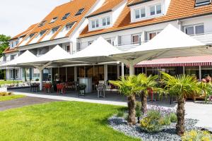 ein Hotel mit weißen Sonnenschirmen vor einem Gebäude in der Unterkunft Europe Haguenau – Hotel & Spa in Haguenau