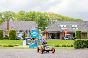 un niño montando un coche de juguete en una calle en TopParken – Landgoed de Scheleberg, en Lunteren