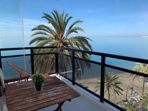 a balcony with a bench and a palm tree and the ocean at Skol Apartments Marbella in Marbella