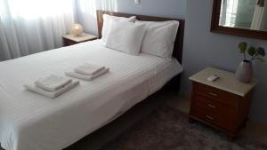 a bedroom with a white bed with two towels on it at Family apartments in Missolonghi