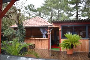 een klein huis met een houten terras in een tuin bij Chez Augustin in Lacanau-Océan