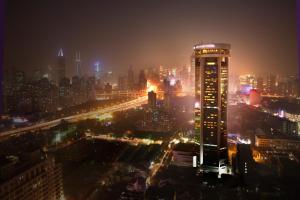 une vue sur la ville la nuit avec un grand bâtiment dans l'établissement Jin Jiang Tower, à Shanghai