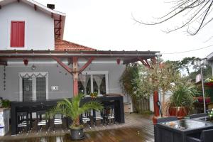 ein Haus mit einer Terrasse mit Tischen und Stühlen in der Unterkunft Chez Augustin in Lacanau-Océan
