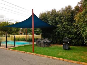 une tente bleue dans l'herbe à côté d'une piscine dans l'établissement Kyabram Motor Inn, à Kyabram