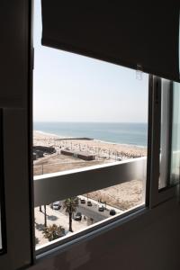 een raam met uitzicht op het strand bij A Nossa Casa da Costa in Costa da Caparica