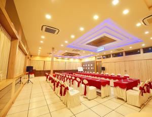 a banquet hall with red and white tables and chairs at Hotel Sanman Gardenia in Bangalore