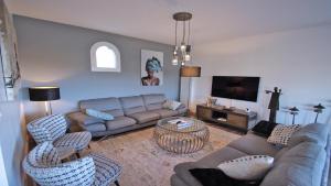 a living room with a couch and chairs and a tv at Les Geais - Marevalande in Sainte-Maxime