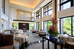 Un comedor con mesas y sillas y ventanas. en THE HIRAMATSU HOTELS & RESORTS GINOZA OKINAWA, en Ginoza