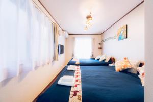 a room with three beds with blue blankets at nestay suite tokyo shibuya in Tokyo