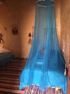 a bed with a blue mosquito net in a room at Kasbah Luna del Sur in Merzane
