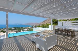 un patio con tavolo, sedie e piscina di Villa Allegra with pool in Pefkos, Lindos area a Pefki Rhodes