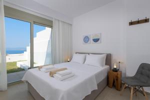 a white bedroom with a large white bed and a chair at Villa Allegra with pool in Pefkos, Lindos area in Pefki Rhodes +18 photos