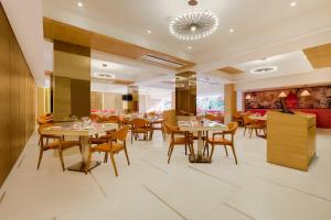 a restaurant with tables and chairs in a room at Red Fox by Lemon Tree Hotels, Vijayawada in Vijayawāda