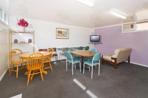 uma sala de espera com mesas e cadeiras e uma televisão em Carrum Downs Motel em Carrum Downs
