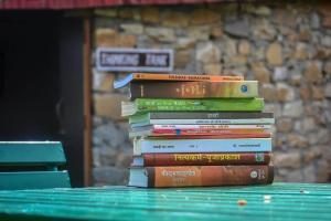 una pila de libros sobre una mesa verde en Tathastu Resort en Mukteswar