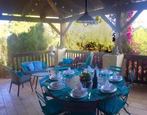 eine Terrasse mit blauen Tischen und Stühlen sowie einer Pergola in der Unterkunft Grande Villa, Corse du Sud, Domaine privé de Cala Rossa in Porto-Vecchio