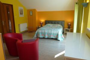 1 dormitorio con 1 cama y 2 sillas rojas en VILLA CHANTAL, en Verdún