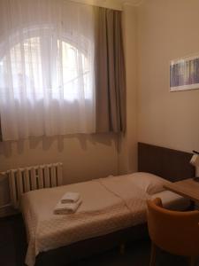 een slaapkamer met een bed, een raam en een bureau bij Hotelik Elka-Sen in Szczecin