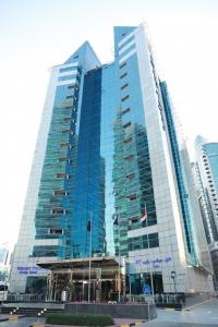 a large glass building with flags in front of it at Golden Tulip Media Hotel in Dubai