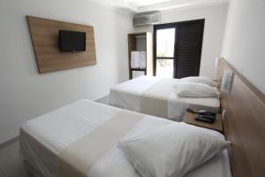 a bedroom with two beds and a tv on the wall at Hotel Recreio São Jorge in Jaboticabal
