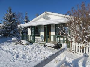 una casa con una veranda verde nella neve di That Country Place B&B a Hanna