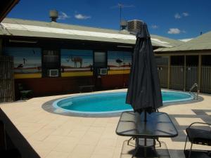 um guarda-chuva sentado numa cadeira ao lado de uma piscina em Broken Hill Tourist Lodge em Broken Hill