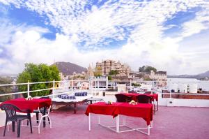 a patio with red tables and chairs on a balcony at The Lake View Hotel- On Lake Pichola in Udaipur