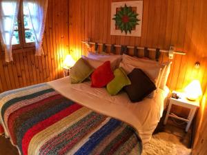 ein Schlafzimmer mit einem Bett mit bunten Kissen in der Unterkunft Pousada Villa D'Amore in Monte Verde
