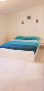 a white bed with blue sheets in a white room at House Mergi in Pomer