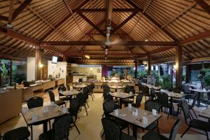 a restaurant with tables and chairs in a room at Kuta Central Park Hotel in Kuta
