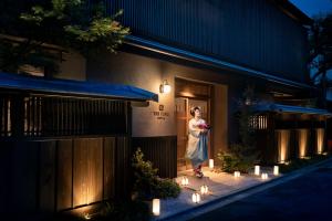 a woman standing outside of a building with lights at THE JUNEI HOTEL Kyoto Imperial Palace West in Kyoto