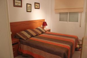 a bedroom with a bed with a striped blanket at Apartamento Cascadas - Deniasol in Denia