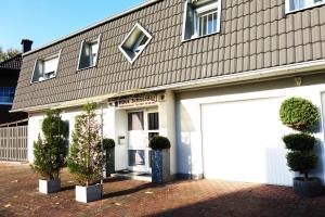 a building with a white garage and potted plants at Aparthotel Messe Flughafen in Düsseldorf