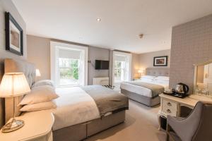 a bedroom with two beds and a desk with a lamp at Belmont House Hotel in Banbridge