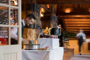 a man standing behind a table with food on it at Hotel Le Palace des Neiges in Courchevel