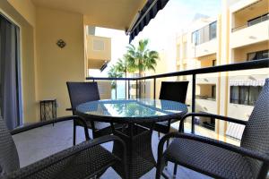 un patio con tavolo in vetro e sedie sul balcone. di Estepona Port Apartment LUNA a Estepona