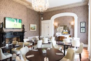a dining room with tables and chairs and a television at Belmont House Hotel in Banbridge