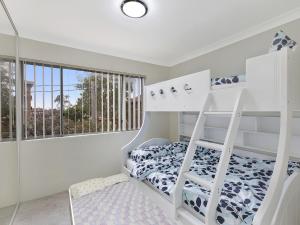 a white bedroom with a bunk bed and a window at Mariners Apartment 21 in The Entrance