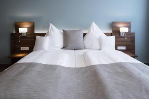 a large bed with white sheets and pillows at Apart-Hotel FirstBoarding Bayreuth in Bayreuth