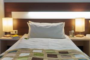 Hotel im Kornspeicher في ماربورغ ان دير لان: غرفة نوم بها سرير مع مصباحين و اللوح الأمامي