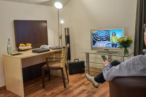 a person sitting on a couch holding a remote in a hotel room at Hotel im Kornspeicher in Marburg an der Lahn