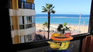 a bowl of fruit on a table with a view of the beach at Marlenghi Apartments View Canteras in Las Palmas de Gran Canaria