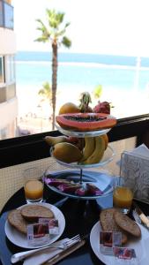 a table with a tray of food on a table with the beach at Marlenghi Apartments View Canteras in Las Palmas de Gran Canaria +26 photos