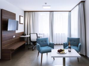 a living room with two chairs and a table and a tv at Apart-Hotel FirstBoarding Bayreuth in Bayreuth