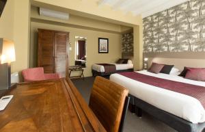 a hotel room with two beds and a desk at Logis Hôtel Le Vert Galant in La Flèche
