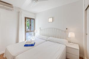 a white bed in a white bedroom with a window at Ana Playasol in Port d'Alcudia