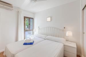 un letto bianco in una camera bianca con finestra di Ana Playasol a Port d'Alcudia