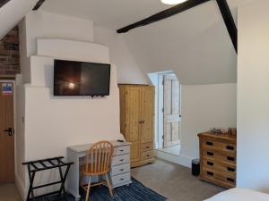 a bedroom with a desk and a tv on the wall at Elderbrook House in Avebury